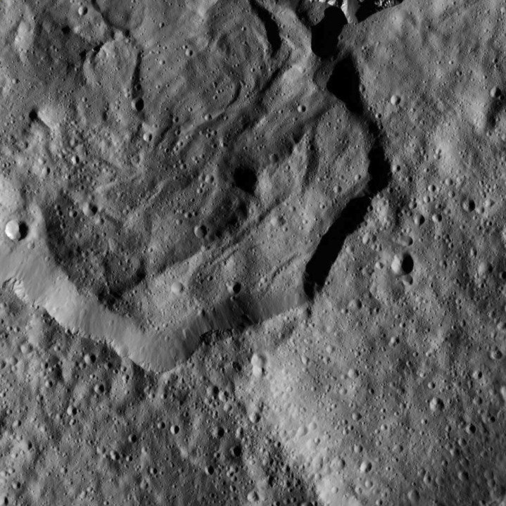 <p>Der Krater Messor mit einem Durchmesser von etwa 42 Kilometern. In der rechten Bildhälfte sind noch die Überreste eines älteren größeren Kraters zu erkennen, den Messor zum Teil überlagert. Auffällig sind auch die wellenförmigen Strukturen am Boden von Messor.</p>