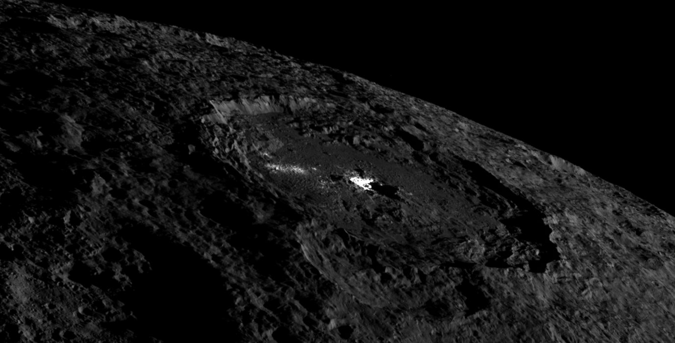 This view of the whole Occator crater shows the brightly colored pit in its center and the cryovolcanic dome. The jagged mountains on the edge of the pit throw their shadows on parts of the pit. This image was taken from a distance of 1478 kilometers above the surface and has a resolution of 158 meters per pixel.